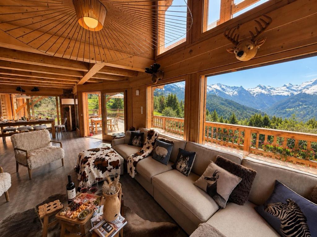 a living room with a couch and a large window at La Framboiseille - Chalet de Luxe avec Piscine Intérieure et Sauna - Vue Montagne in Manigod