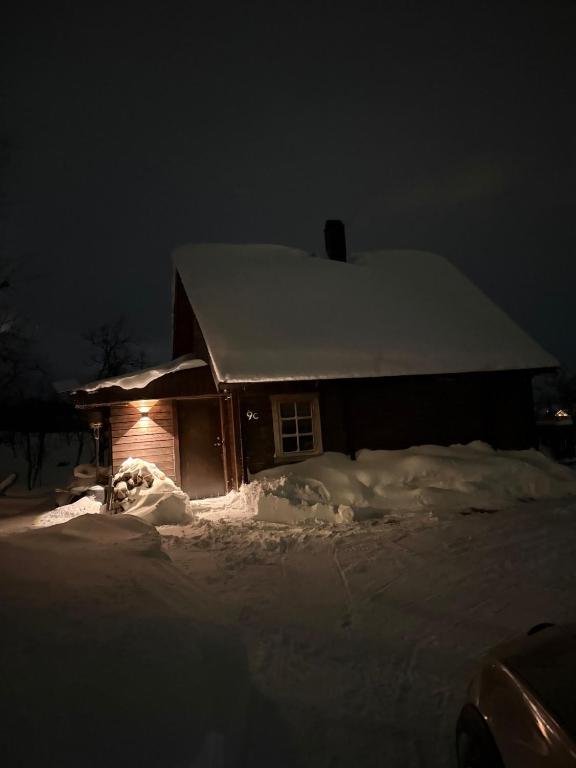 a house covered in snow at night with a light at Hytta Kilpisjärvi in Kilpisjärvi