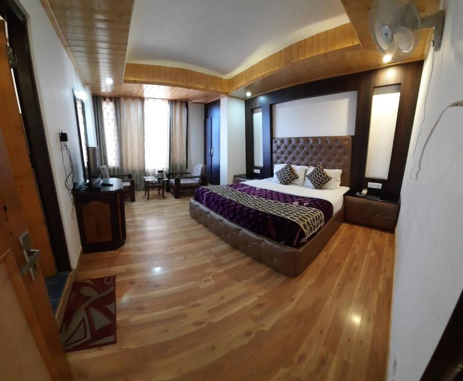 a bedroom with a large bed and a wooden floor at Hotel Lords Regency - Connected to the Mall Road in Shimla