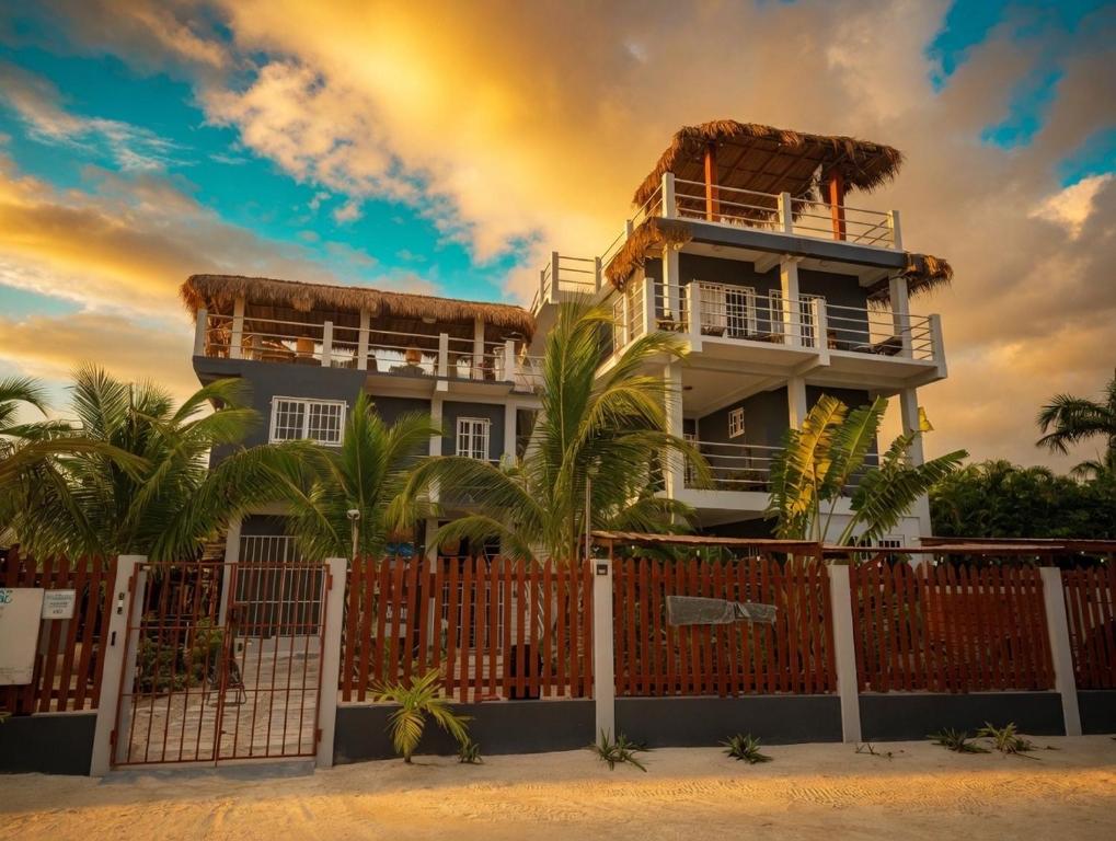 a building with a fence and palm trees at Costa Nube in Caye Caulker