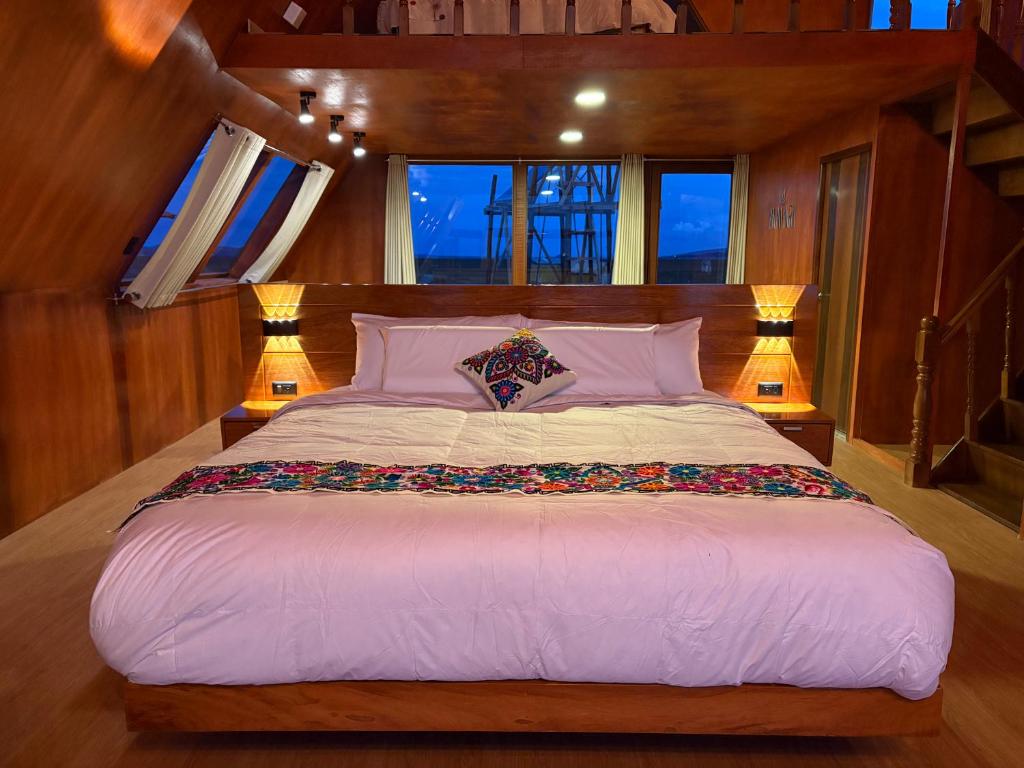 a large bed in a room with two lamps at Titicaca Samca Lodge Puno Peru in Puno