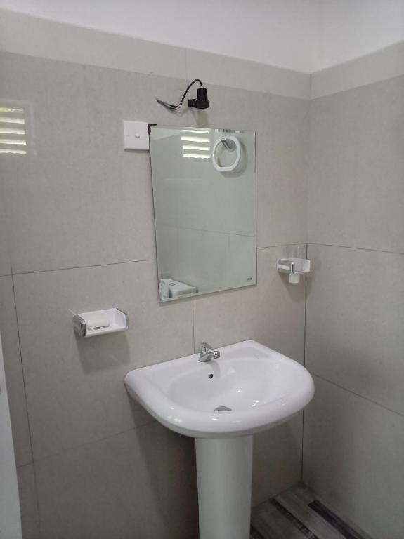 a bathroom with a white sink and a mirror at The Sun Horse Villa in Unawatuna