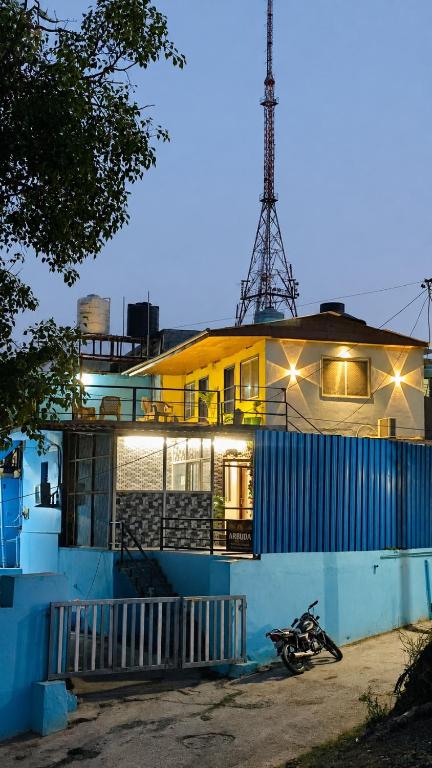 a yellow house with a blue fence in front of it at Arbuda inn in Mount Ābu