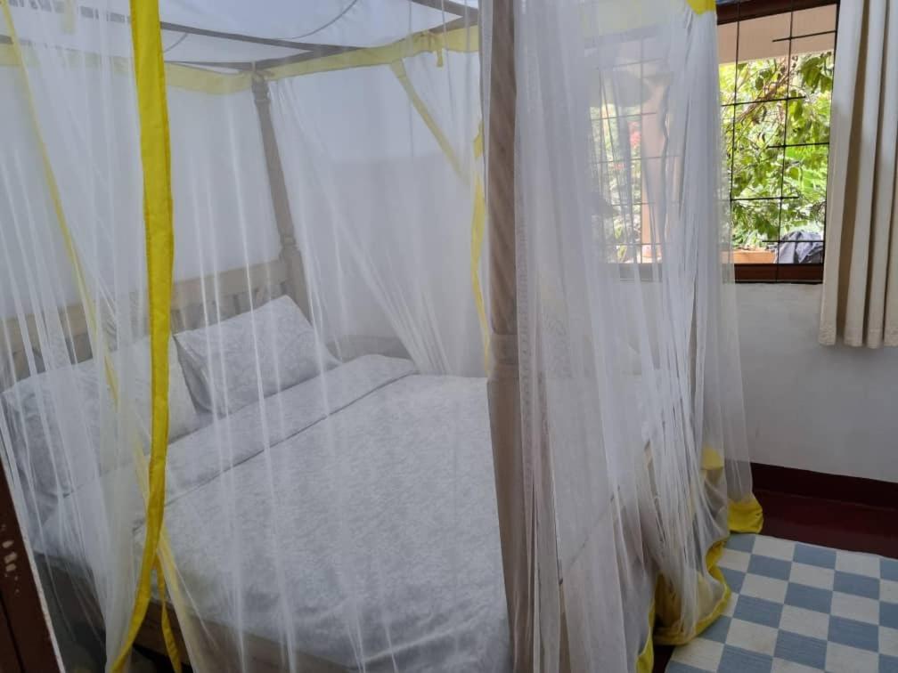 a bed in a room with white curtains at Mary House in Arusha
