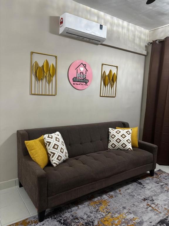 a brown couch in a living room with yellow pillows at RAF Homestay Seri Serindit in Malacca