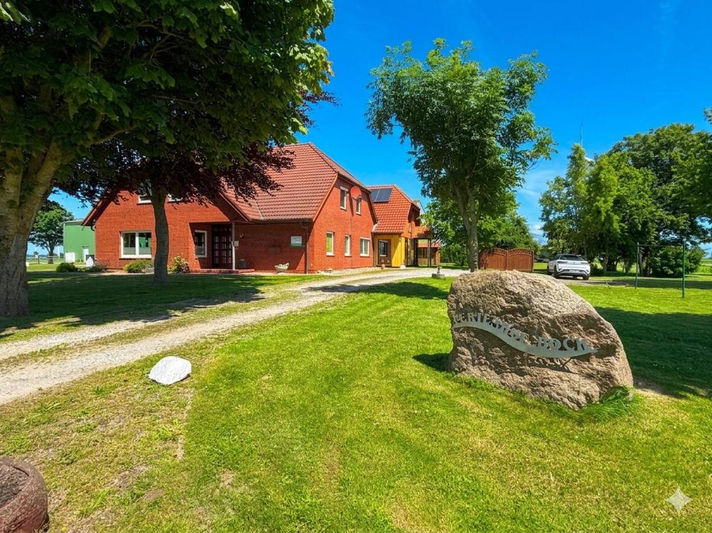 a rock in the grass in front of a house at Ferienhof am Meer in Friedrichskoog