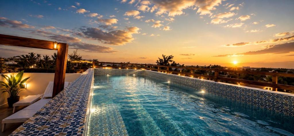 a swimming pool on the roof of a building with a sunset at Hotel Mariel Holbox in Holbox Island