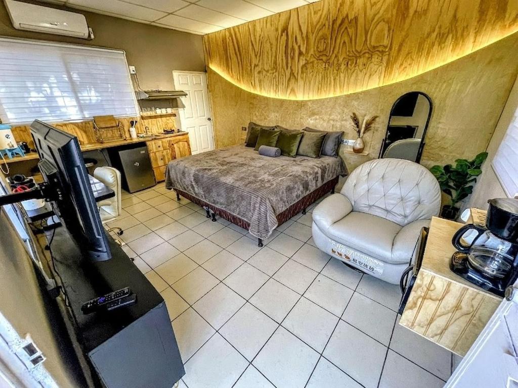 a bedroom with a bed and a tv and a chair at Loft Moderno 2 Netflix # Cama King # Aire acondicionado # Parqueo in Puerto Barrios