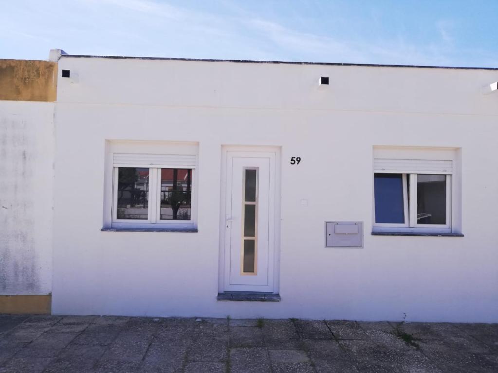 a white building with two windows and a door at Atalaia Garden House in Giz
