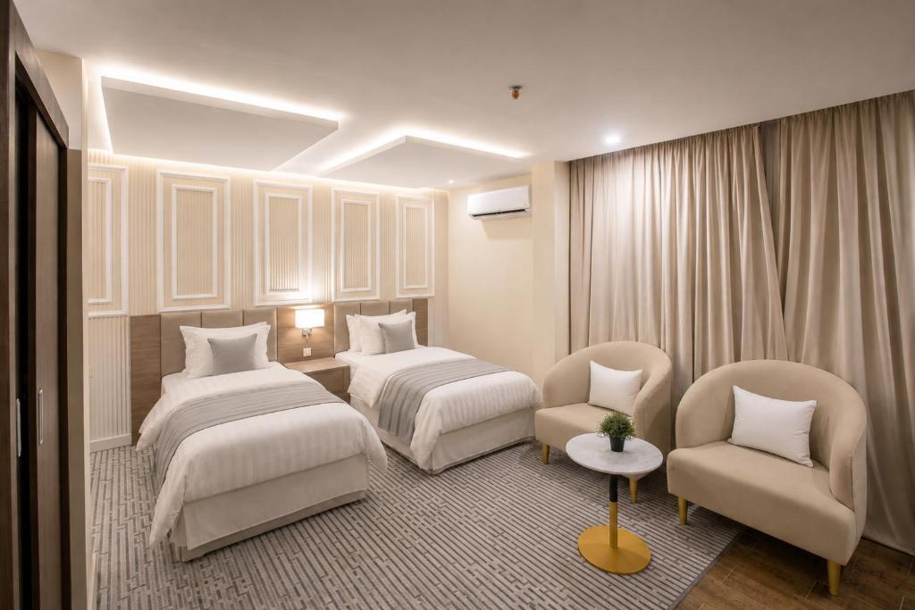 a hotel room with two beds and a chair at فندق حي الربوه Al Rabwah District Hotel in Tabuk
