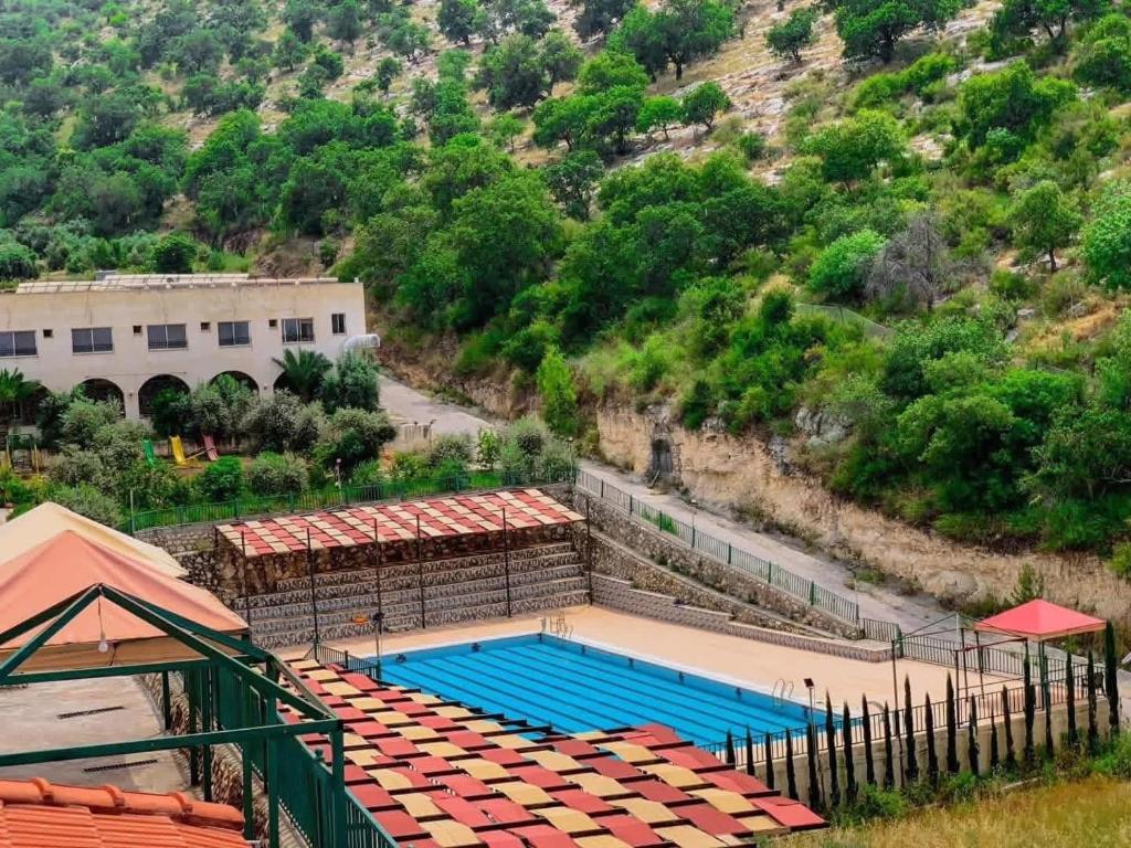 an empty swimming pool with a building and a mountain at Jadara view in Irbid