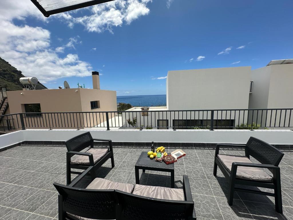 a patio with two chairs and a table with fruit on it at Madalena House in Madalena do Mar