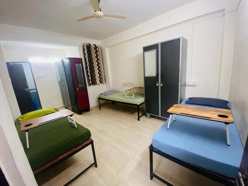 a room with three beds and a ceiling at Alpine Hostel Services in Pune