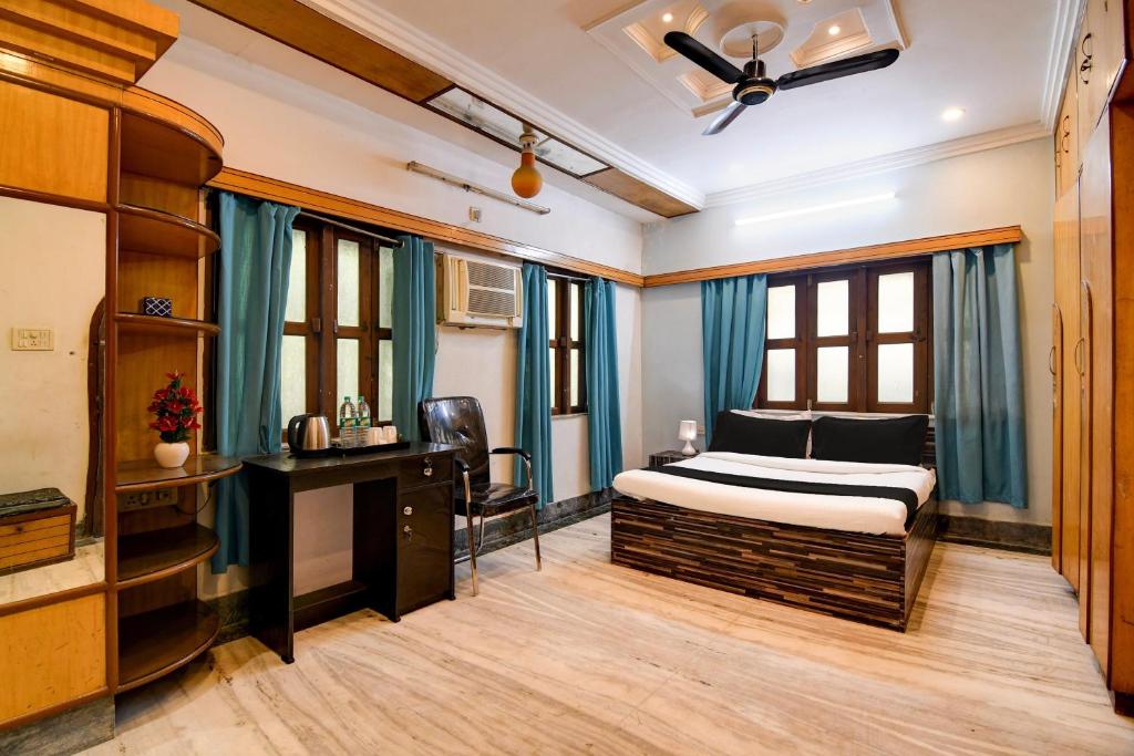 a bedroom with a bed and a desk and windows at Hotel O Avenue Villa in Dum Dum