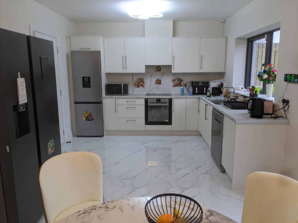 a kitchen with white cabinets and a table and chairs at Hotel vibe at home in Edenderry