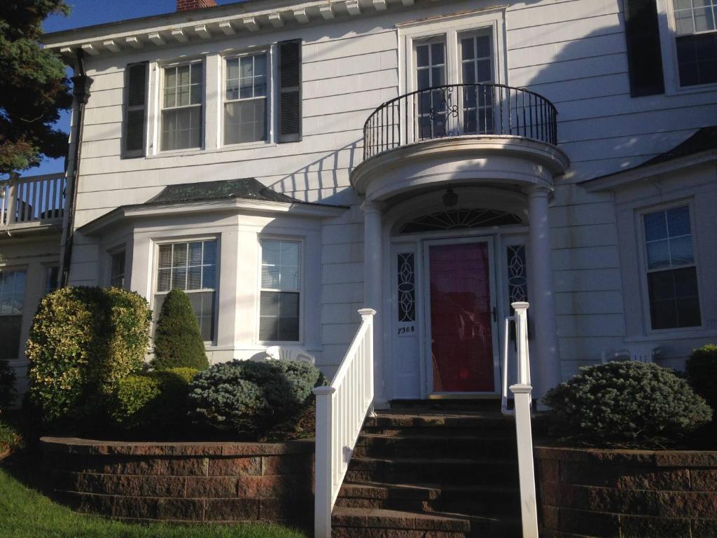 a white house with a red door and stairs at Beach Block Victorian 1 minute from beach in Ventnor City