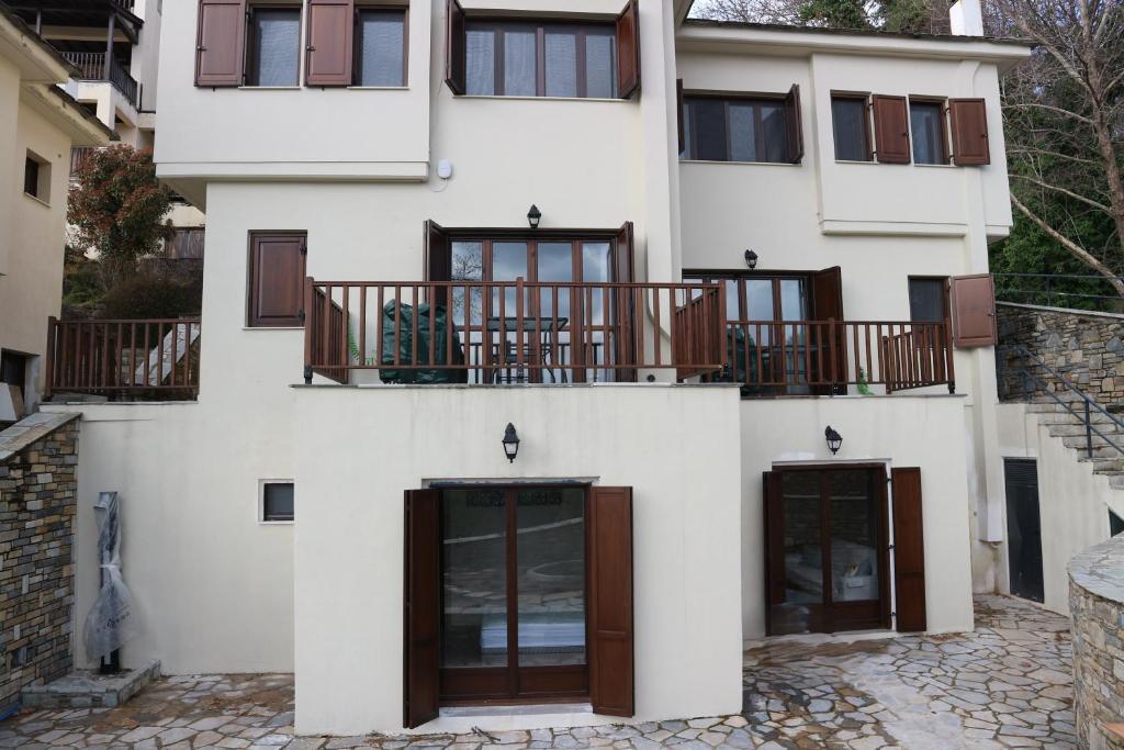 a white building with brown doors and balcony at Villa Elea in Milies Pelion in Mileai
