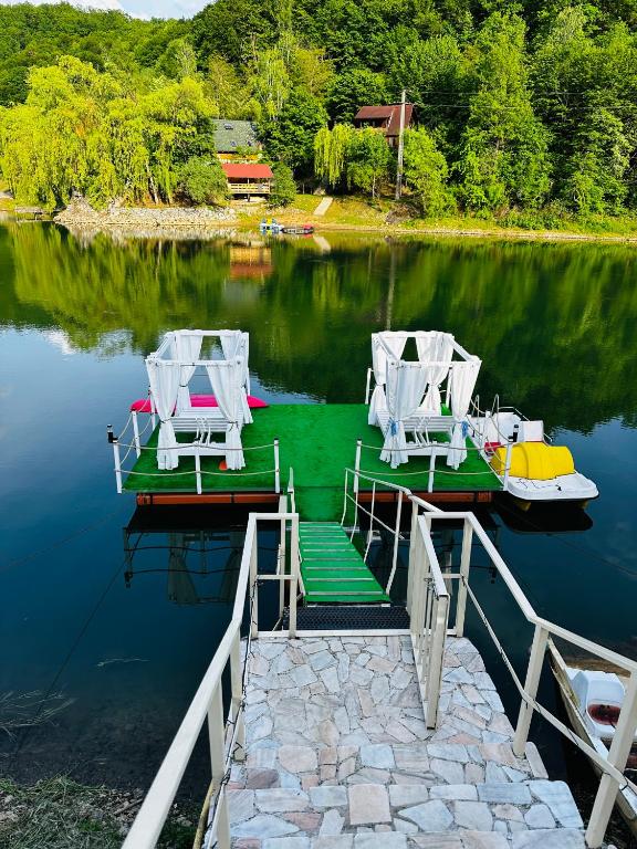 a dock with two chairs and a boat on a lake at Leo Green House in Cinciş