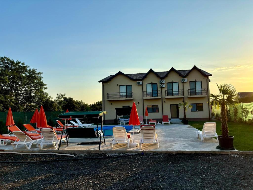a group of chairs and a pool in front of a house at Pensiunea SAUVAGE in Corbu