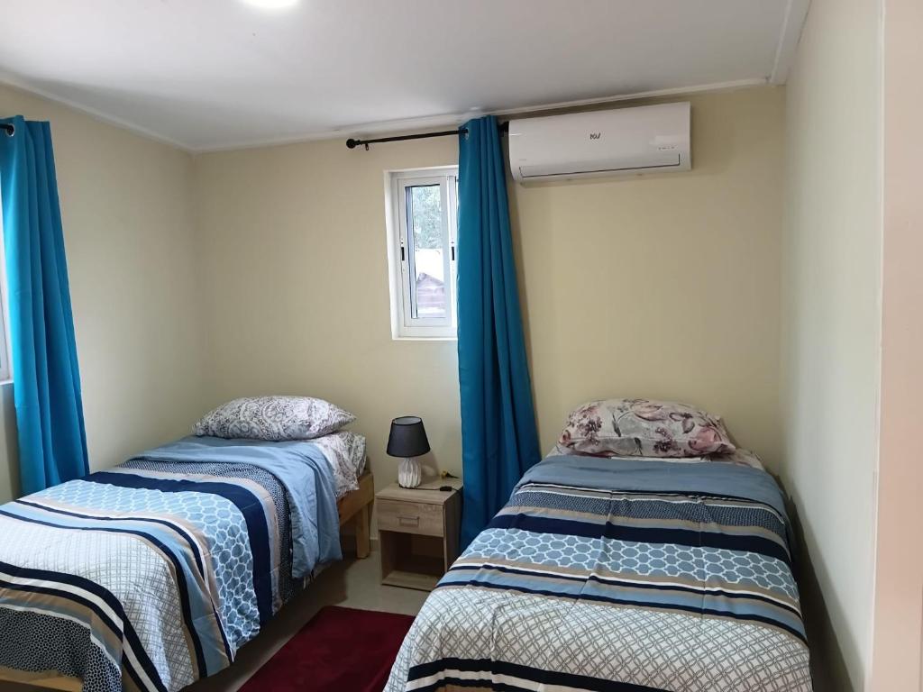 two beds in a room with blue curtains and a window at Sucasa Apartment B in Willemstad