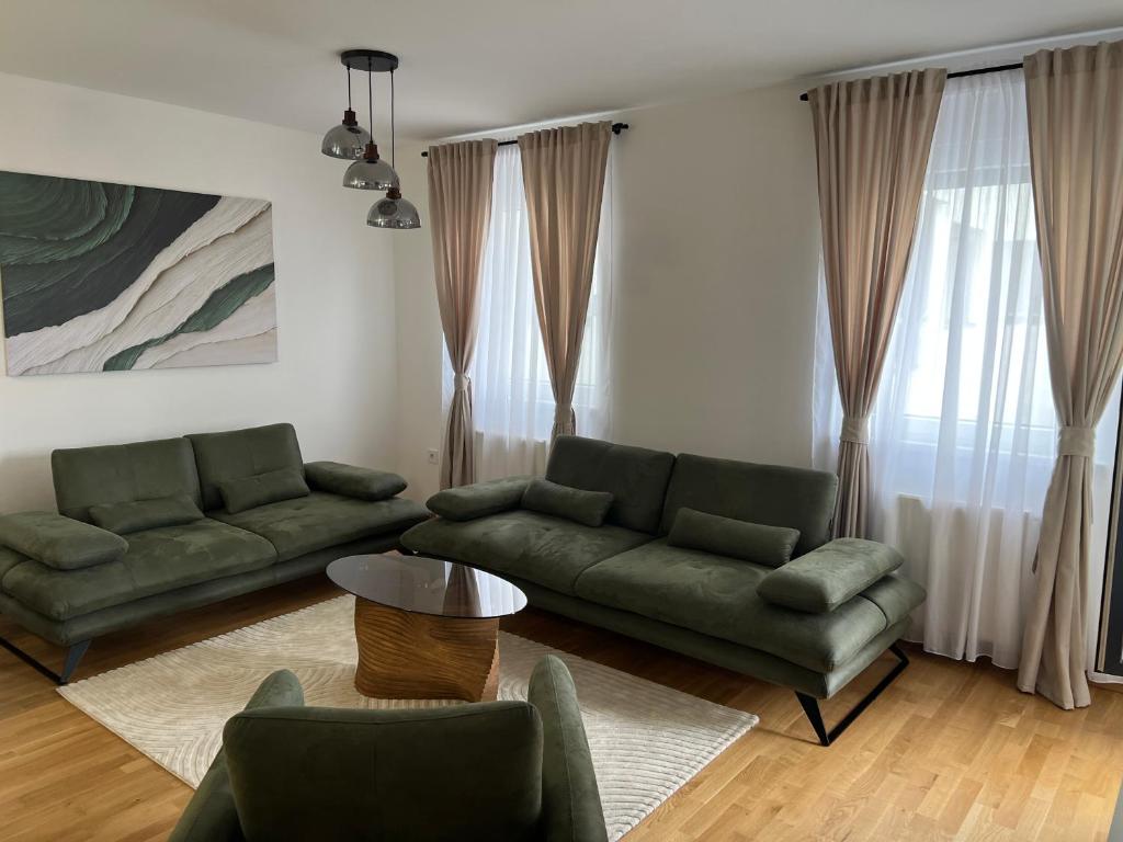 a living room with two green couches and a table at Apartman 15 in Novi Sad
