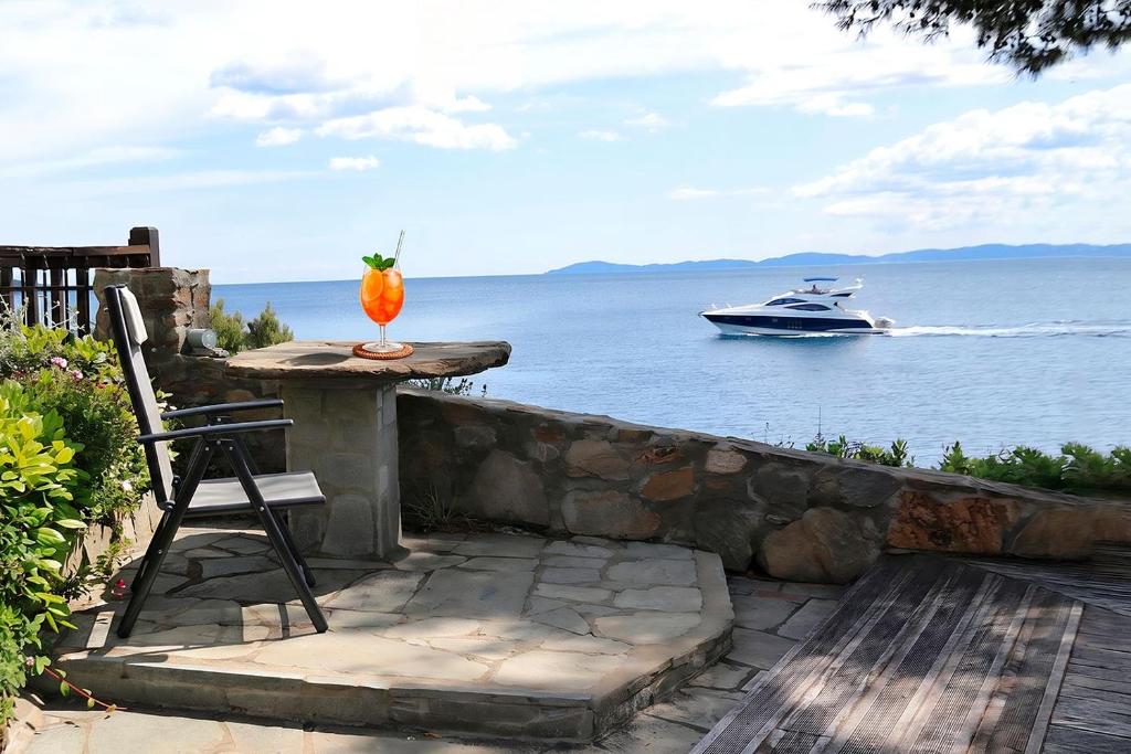 a table with a drink and a boat in the water at FILIPPIDIS suites in Neos Marmaras