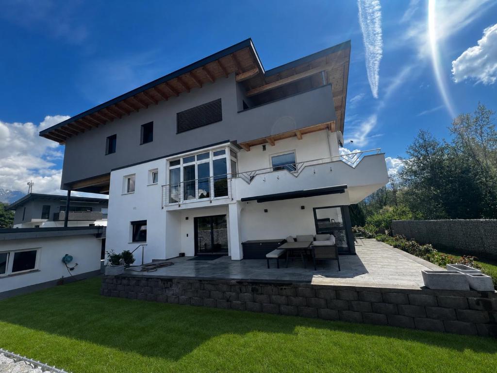 a white house with a patio in the yard at Alpinelodge8 in Innsbruck