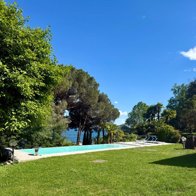 a swimming pool in a park with trees and grass at Casa Blanca - Villa with pool and private beach in Lesa