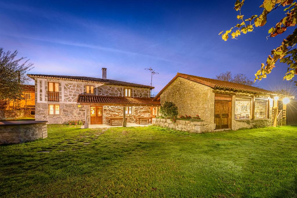 a large stone house with a green yard at CASA DAS XACIAS, RIBEIRA SACRA in A Airoa