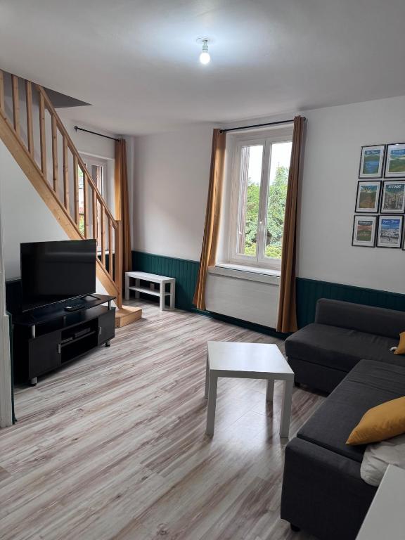 a living room with a couch and a tv at Petit cocon près des grottes de Perrier in Perrier