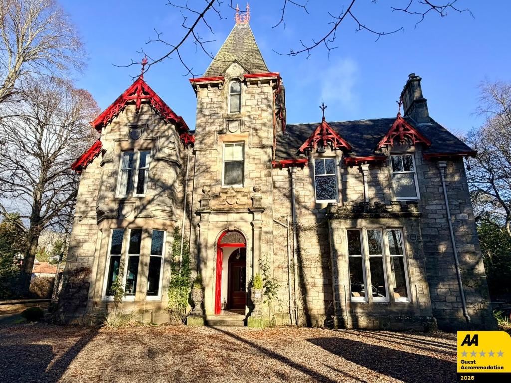 an old stone house with a red door at Birchwood Pitlochry in Pitlochry