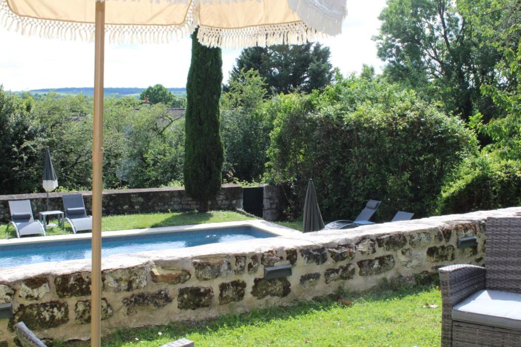 a patio with an umbrella and a swimming pool at Domaine les Feuillants in Crouzilles