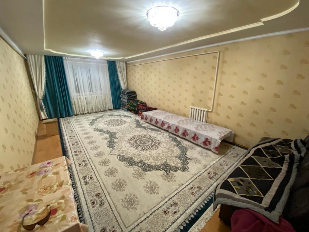 a small room with two beds and a rug at ILGIZ HOUSE Barskoon in Barskoon
