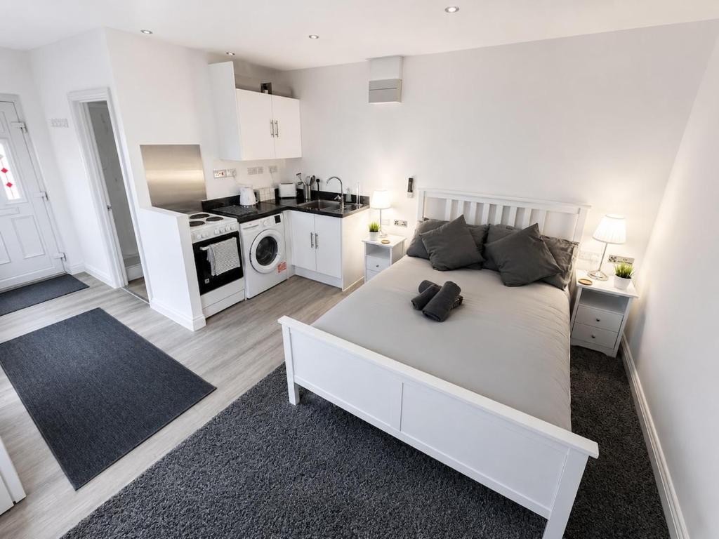 a white bedroom with a large bed and a kitchen at The Studio Room in Brentwood