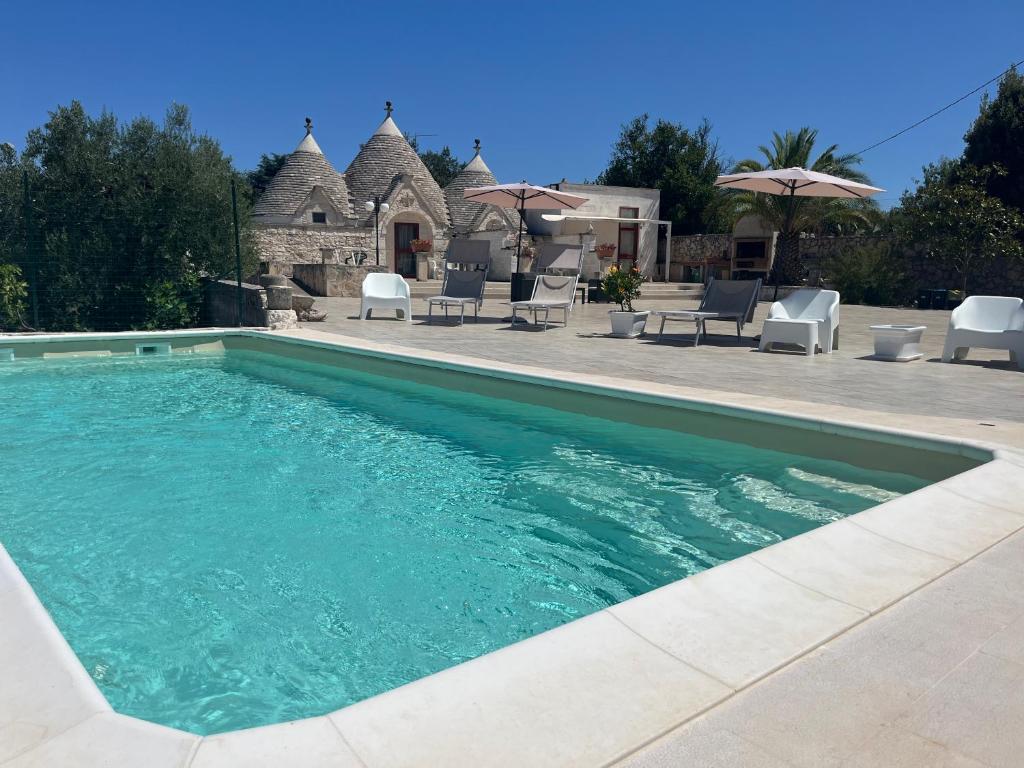 a swimming pool with chairs and a house at Trulli del boschetto in Putignano