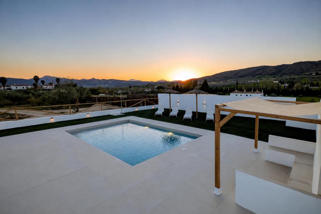 a swimming pool on the roof of a house with the sunset at Casa rural Doble-R in Ronda