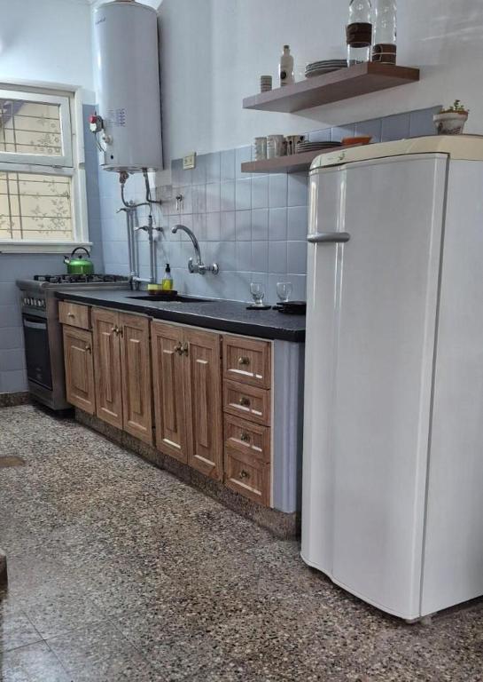 a kitchen with a white refrigerator and wooden cabinets at Día y noche in Ezeiza