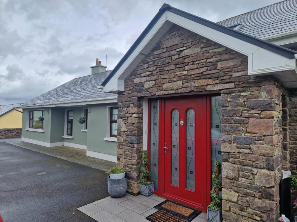 a brick house with a red door in a driveway at Dee's Nest in Dingle
