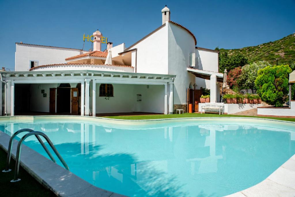 a swimming pool in front of a house at Hotel L'Aragosta in La Caletta