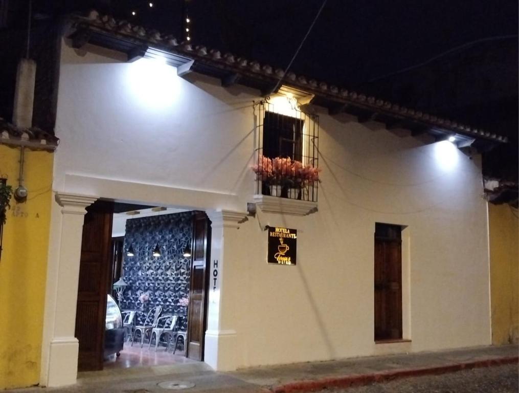a white building with a balcony and a window at night at Hotel & Restaurante Teresàs Bistro in Antigua Guatemala