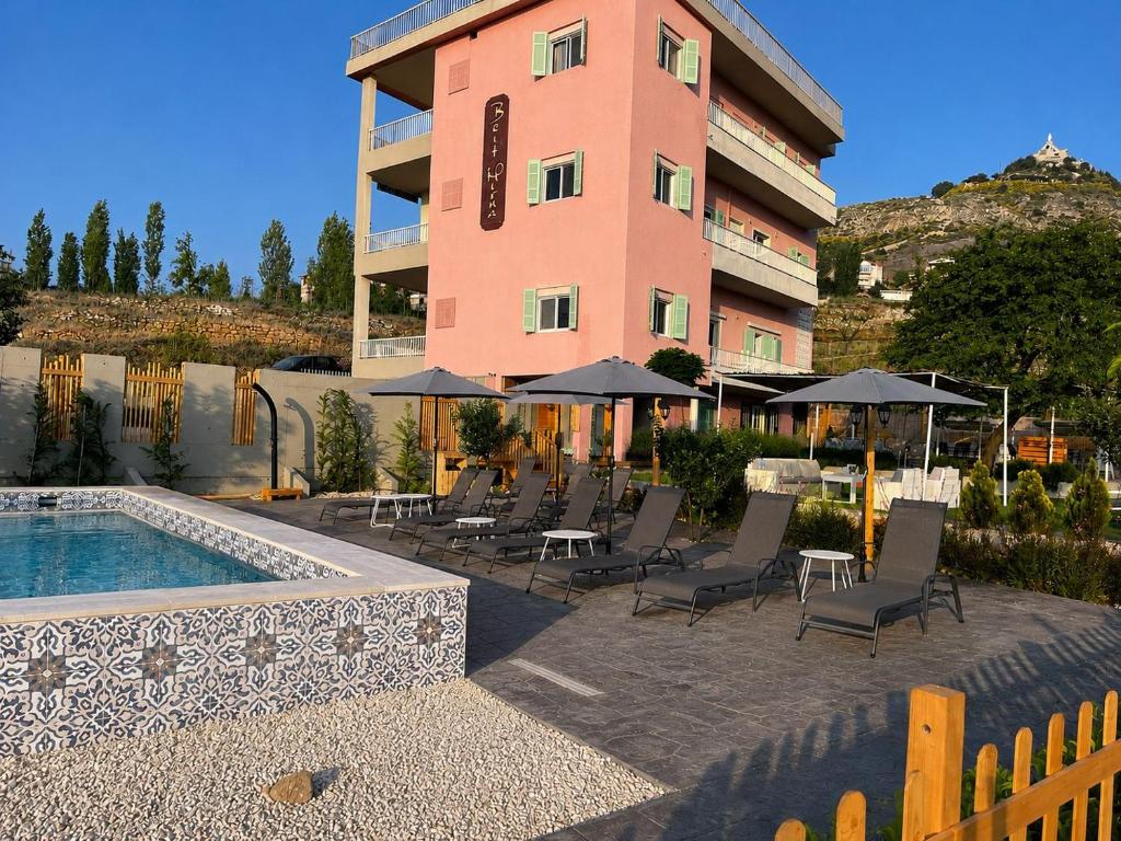 a hotel with chairs and a pool and a building at Beit Mirna Guesthouse & Chalet - Ehden in Ehden