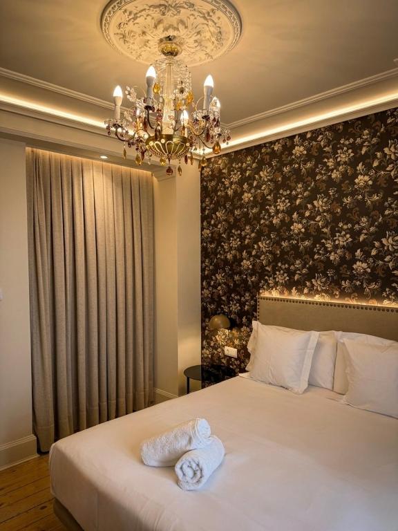 a bedroom with a large white bed with a chandelier at Hostal Boutique Puerta del Sol in Torrelavega