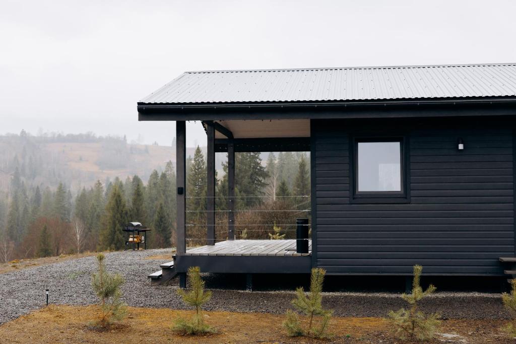 a black cabin with a porch on a hill at Gora vitriv in Slavske