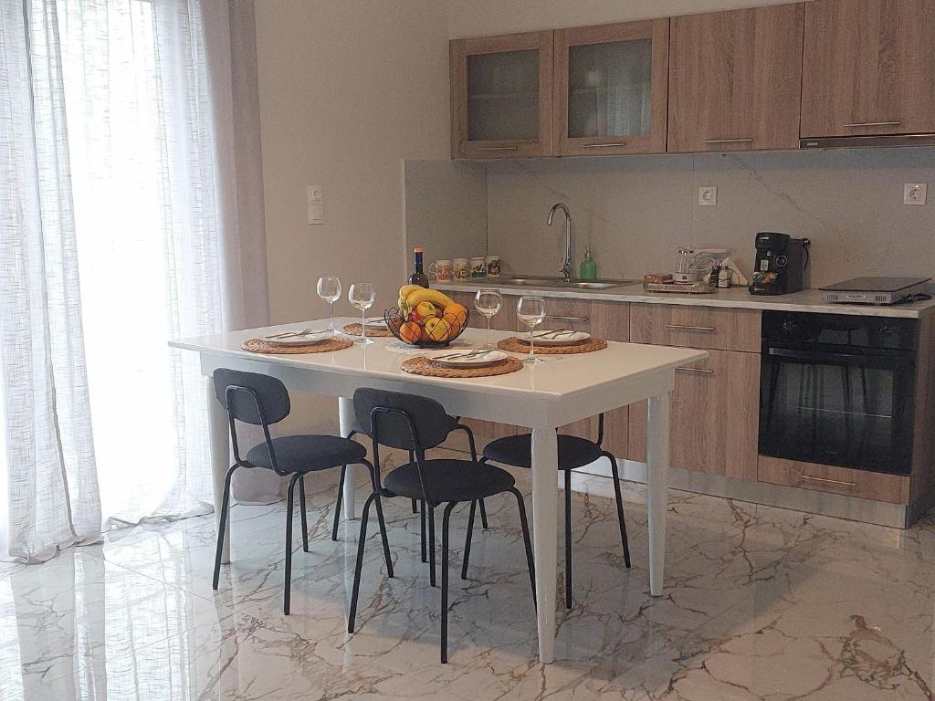 a kitchen with a white table with chairs and wine glasses at Claudia's Apartments in Aliveri