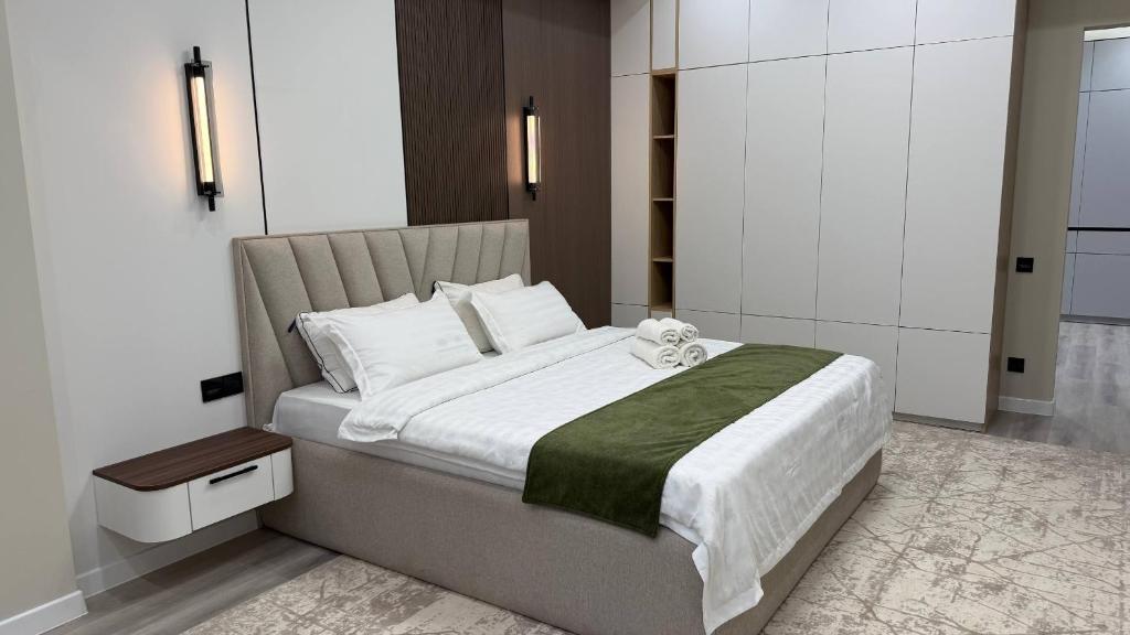 a bedroom with a large bed with white sheets at Zafran Platinum Apartments in Dushanbe