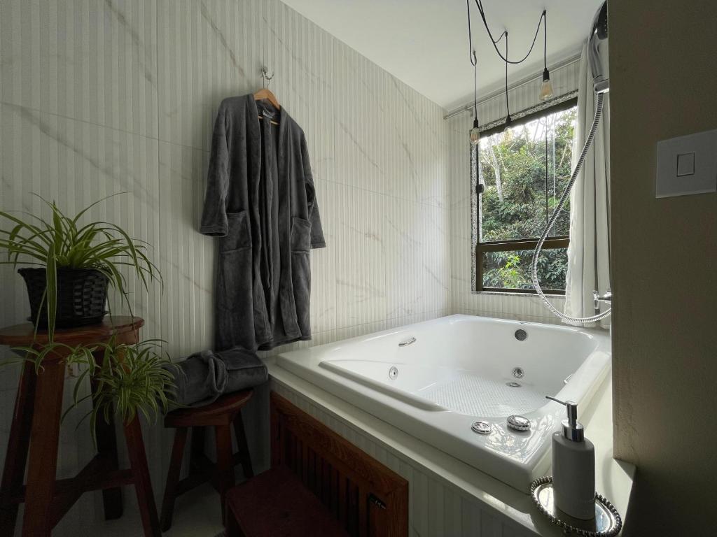 a bathroom with a tub and a robe hanging on a wall at Estância Shangri-La in Santa Teresa