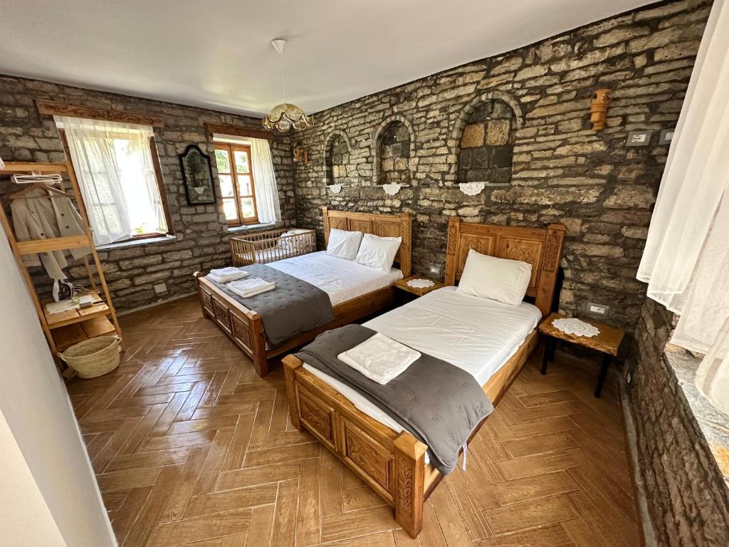 a bedroom with two beds and a stone wall at Anderr stone Boutique in Gjirokastër