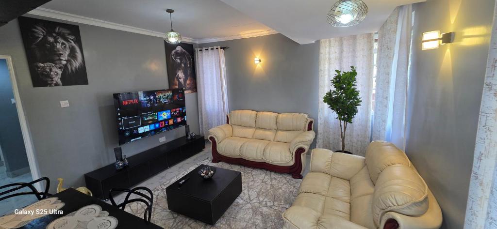 a living room with couches and a flat screen tv at The Amanda Bed & Breakfast in Migori