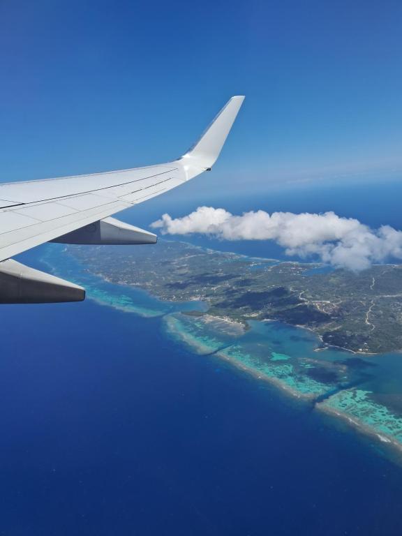 an airplane wing flying over the islands in the ocean at Blue Horizon Studios in Roatán