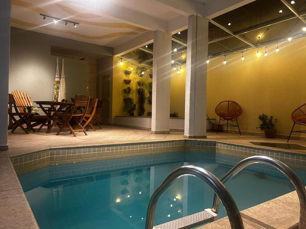 a swimming pool with a patio and a table and chairs at Hotel Thermas da Mantiqueira - Poços de Caldas - De frente para a Praça Central in Poços de Caldas